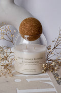 Designer scented candle in a glass jar with a ball‑shaped lid